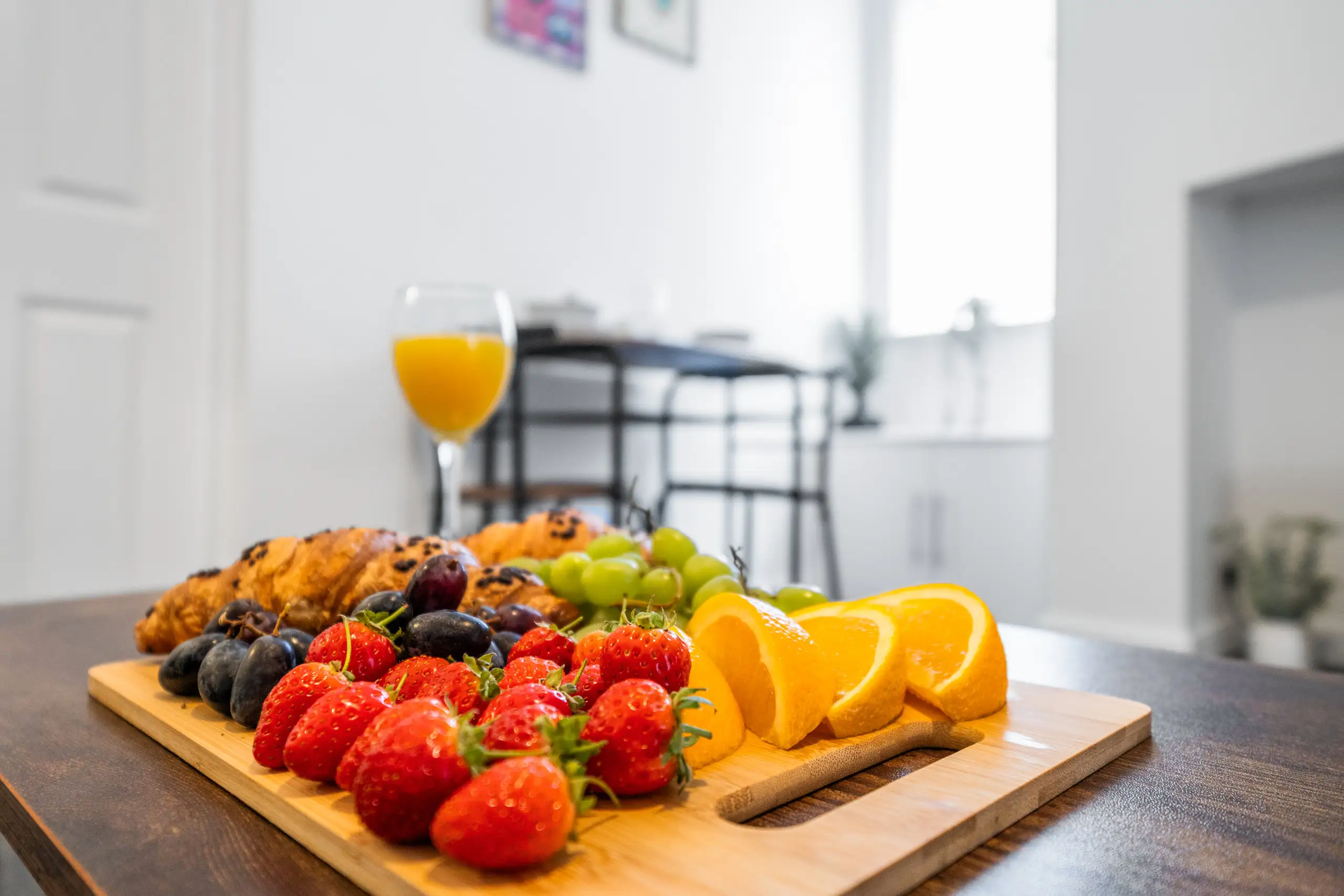 Strawberries, orange slices, grapes and pastries on a wooden board