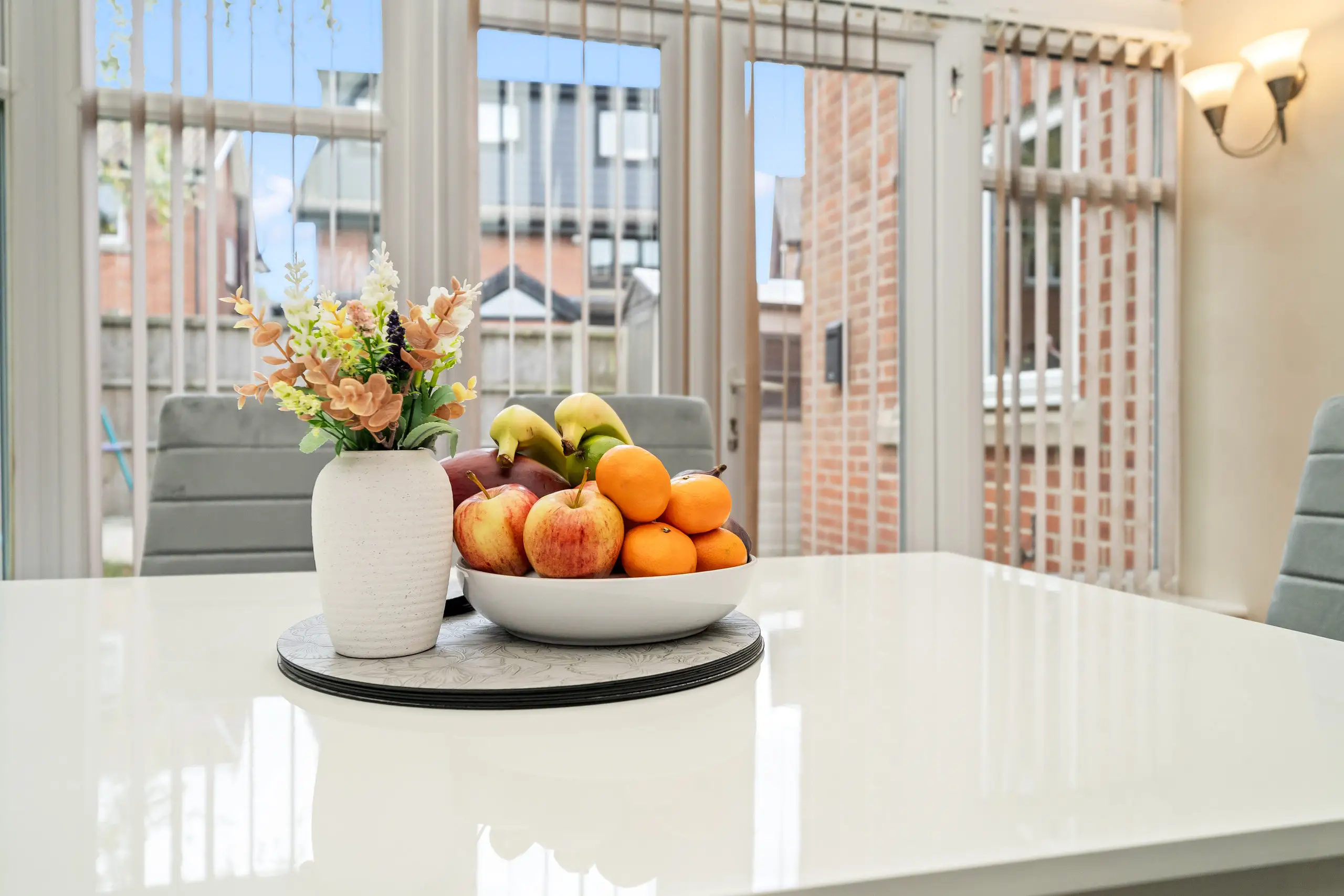 Fruit bowl and flowers on a white dining table in the conservatory