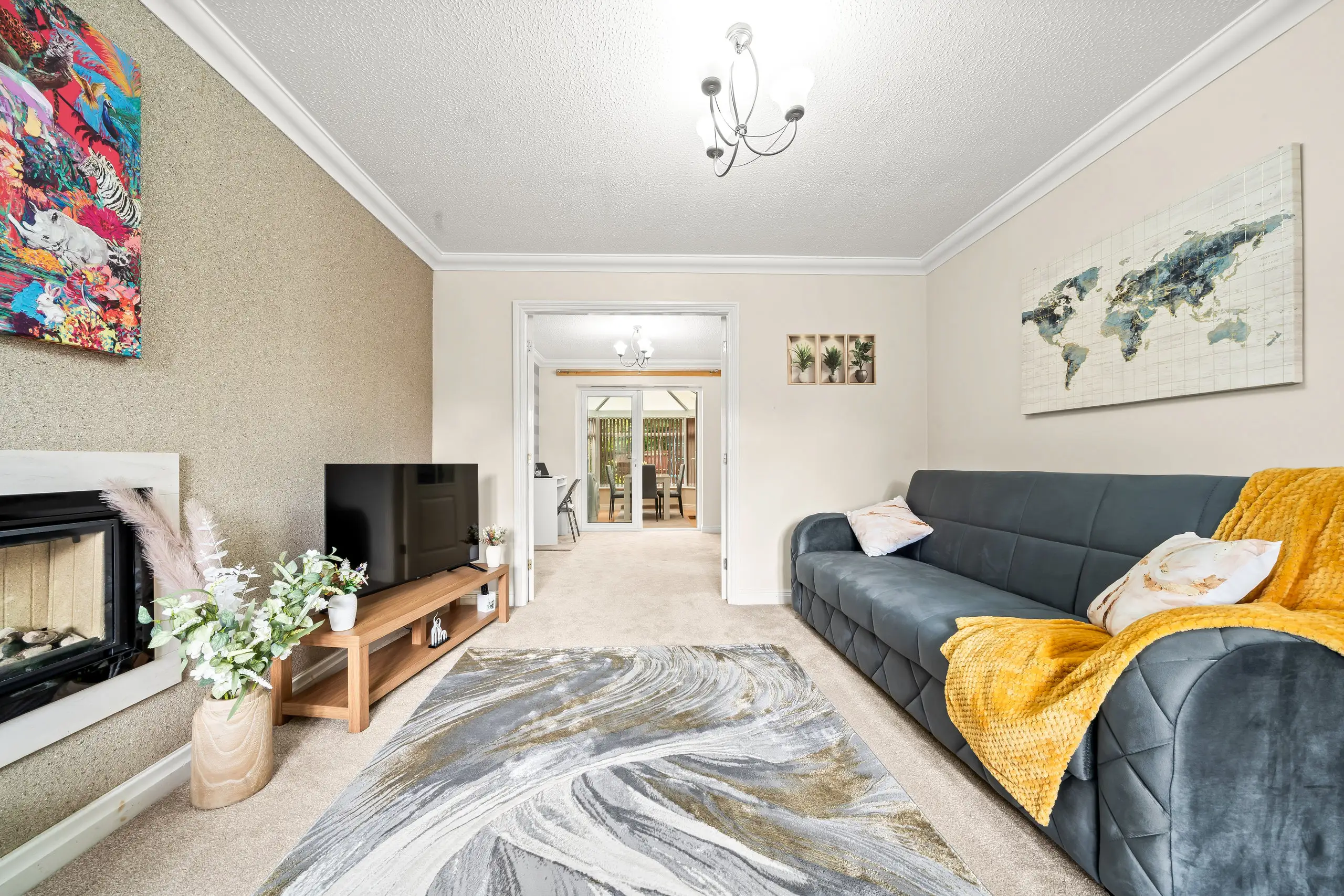 Living room with a teal sofa, mustard throw and fireplace, looking through to the conservatory