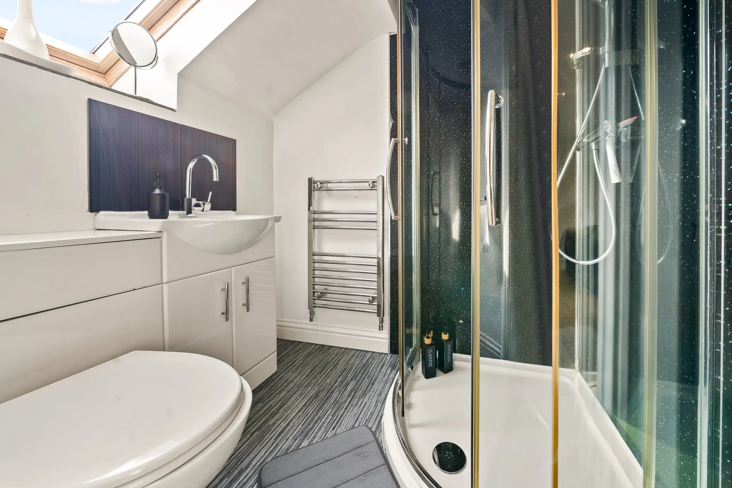 Shower room with a corner shower enclosure, vanity unit, heated towel rail and roof window