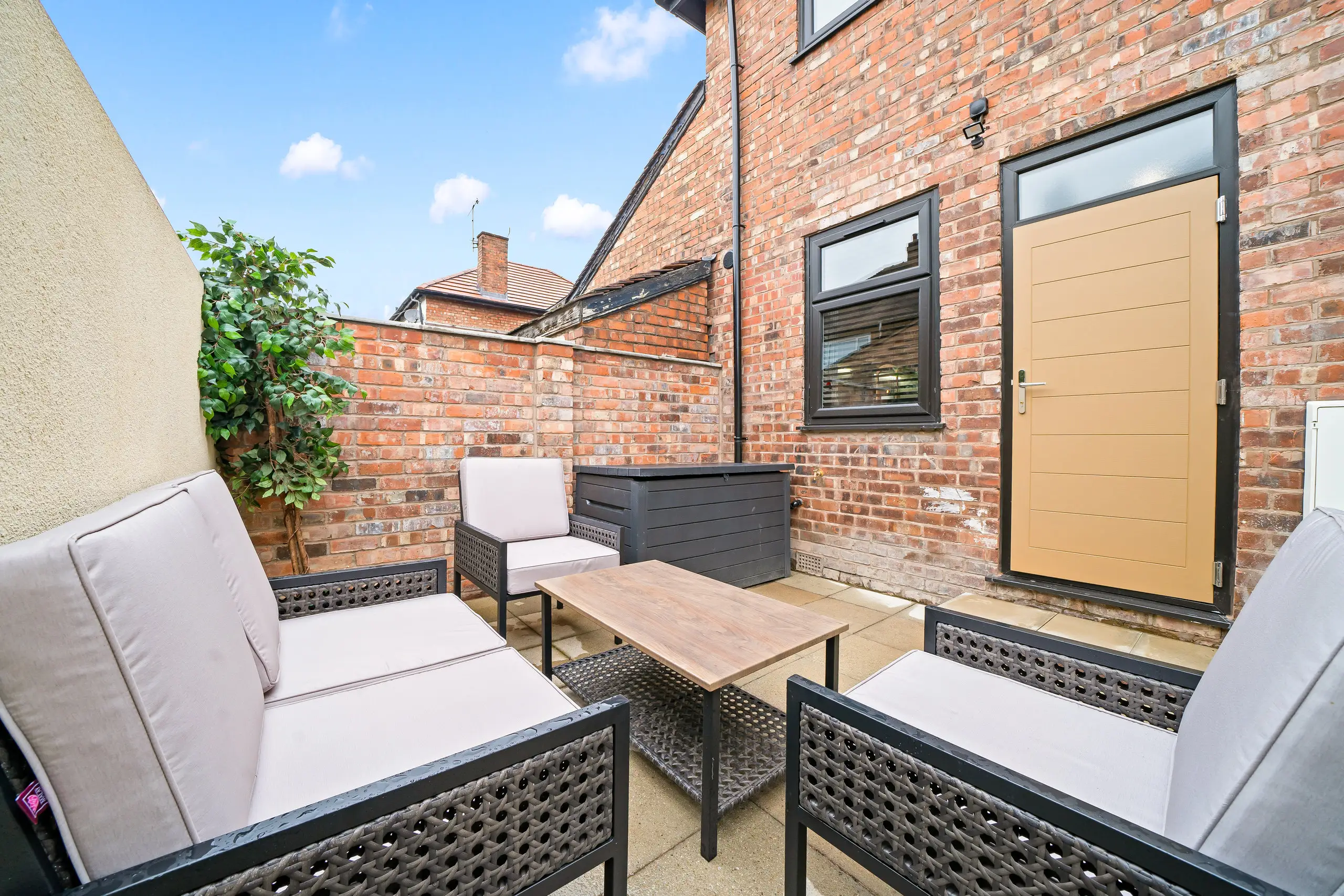 Paved patio with outdoor sofa and chairs between brick walls