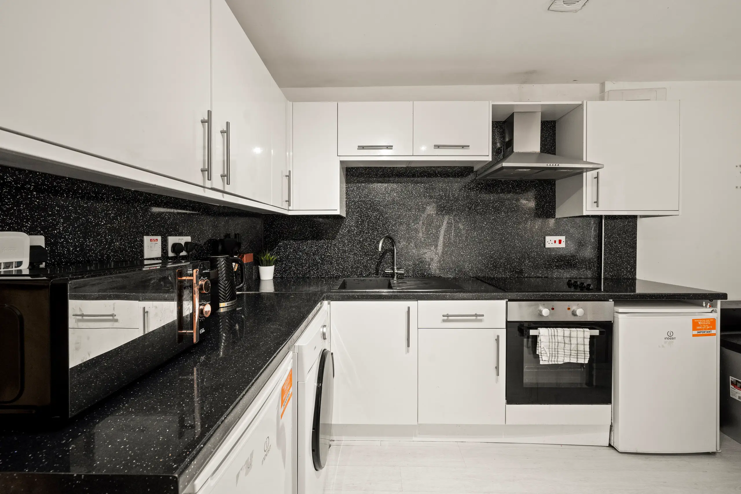 White gloss kitchen with black sparkle-effect worktops and splashback