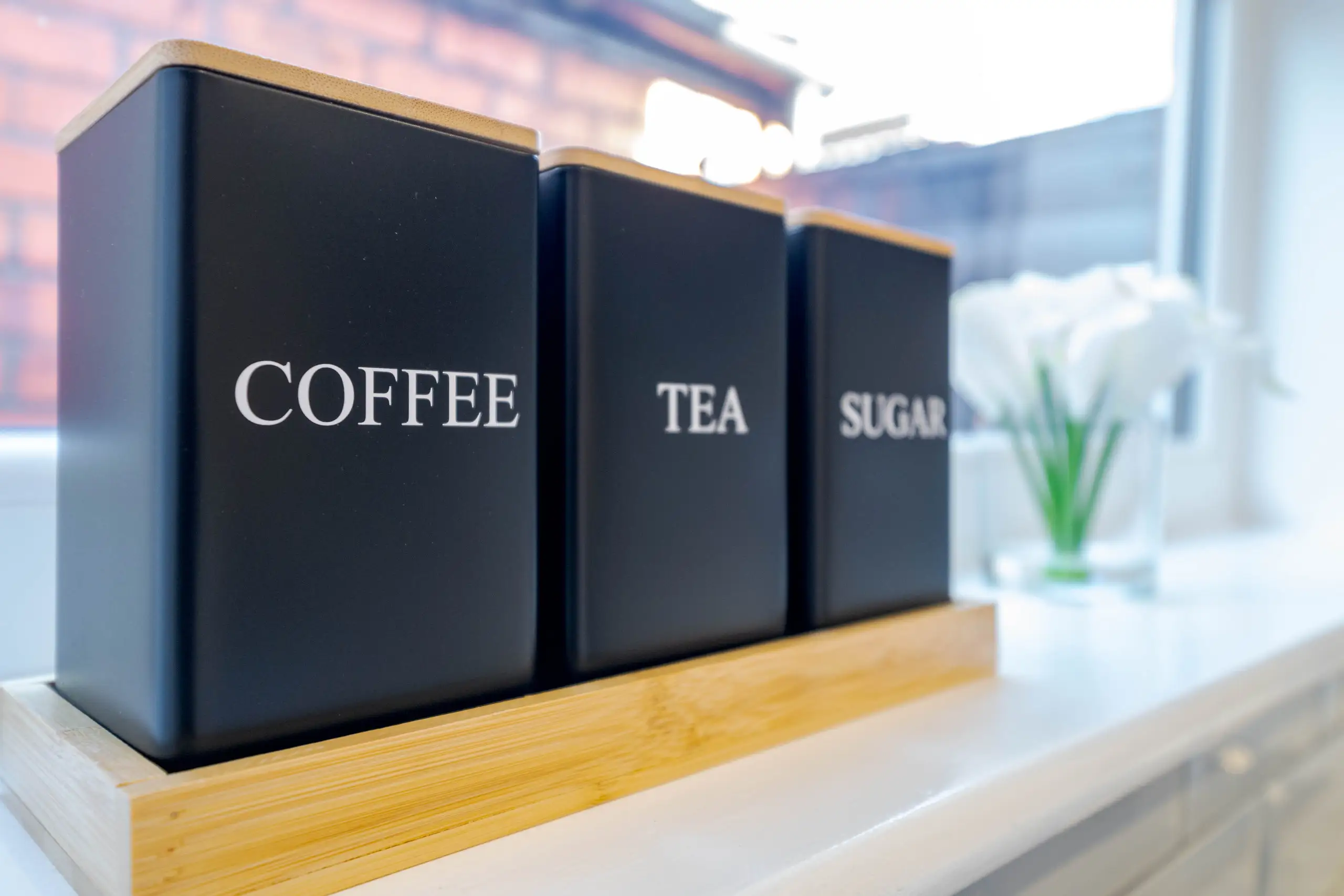 Coffee, tea and sugar canisters on a kitchen windowsill