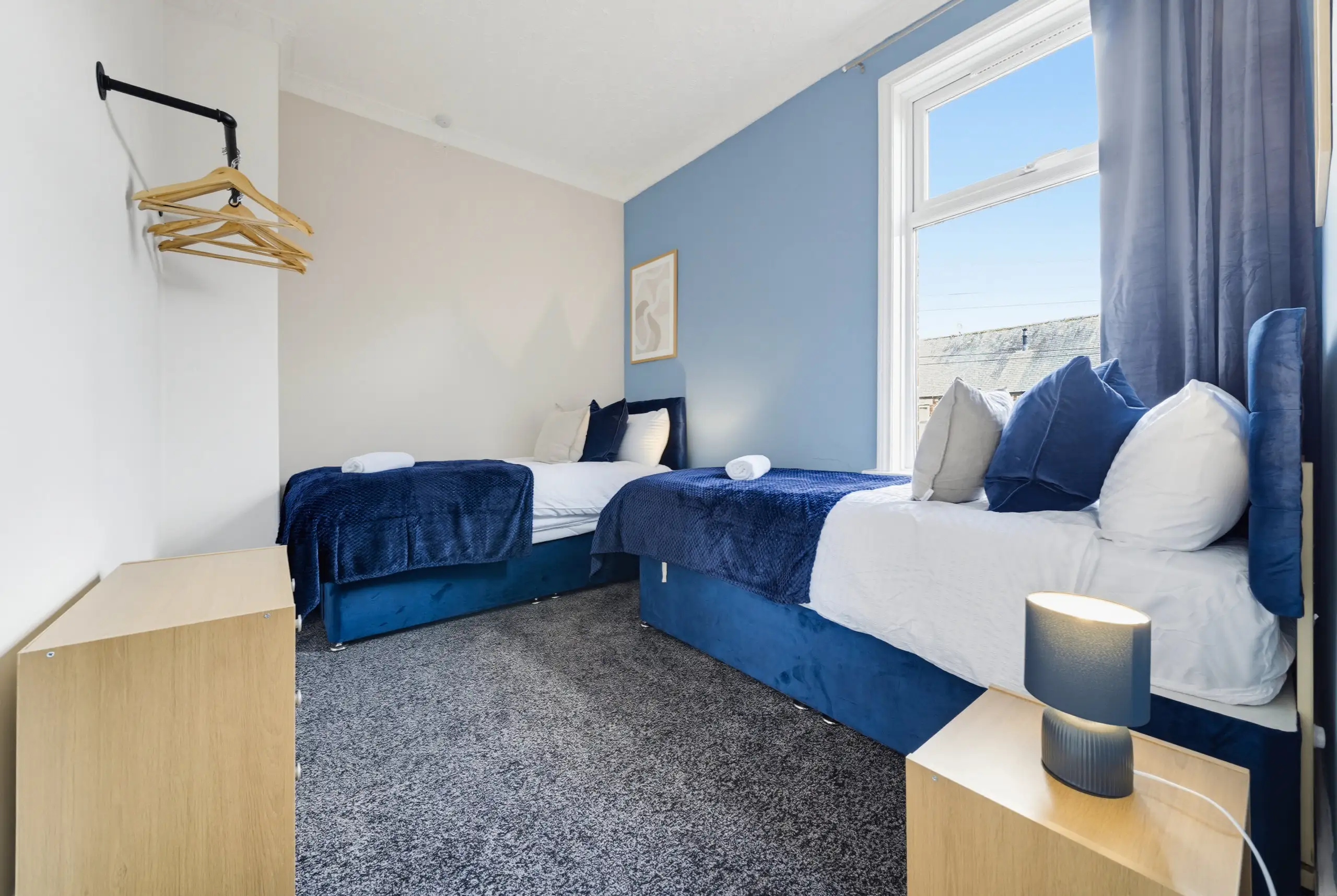 Twin bedroom with navy throws and a blue feature wall