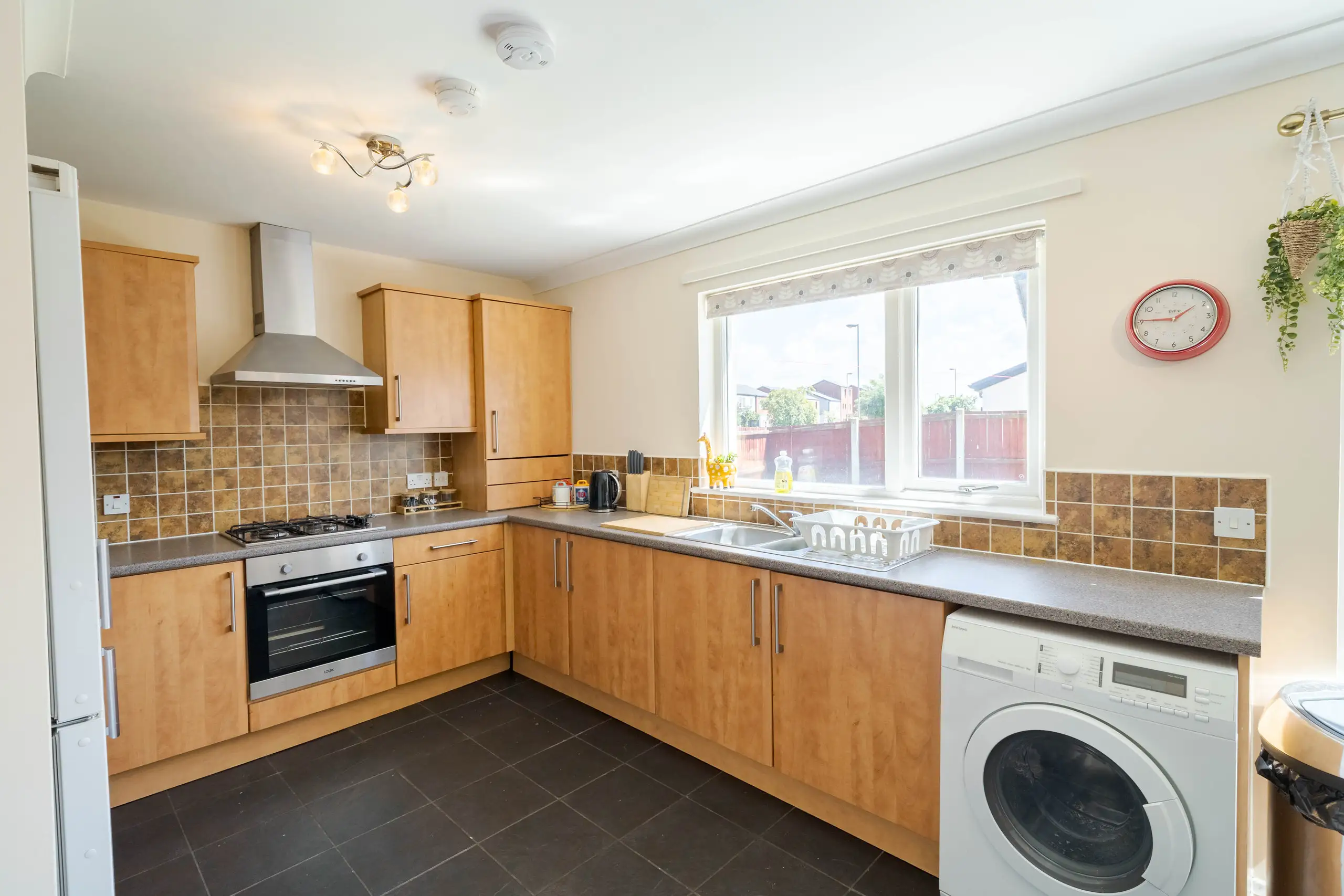 Kitchen with wood-effect units, a tiled splashback and a window over the sink